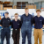 Four aircraft apprentices stand shoulder-to-shoulder in an empty hangar