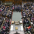 A busy House of Commons packed with sitting MPs as photographed from above. Prime Minister Rishi Sunak leans against the podium as he speaks.